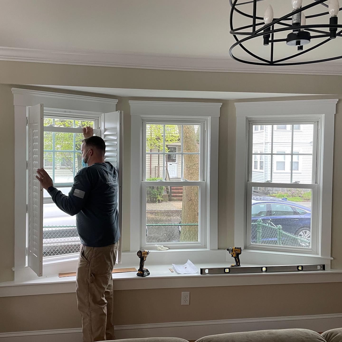 Melmar installer fitting plantation shutters in a residential bay window